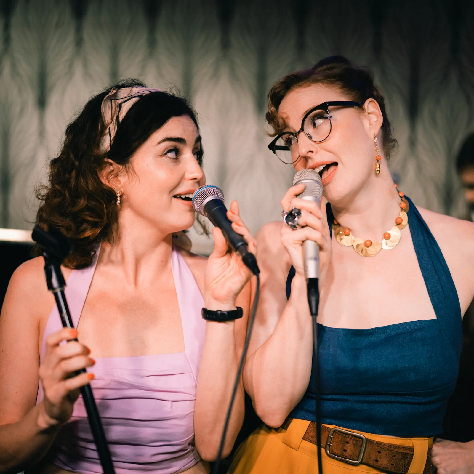 Dos cantantes interpretan una canción juntas con micrófonos durante una actuación en directo.